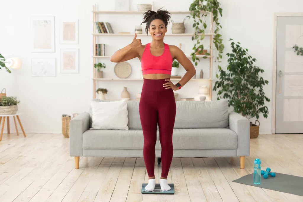 happy girl in gym clothing standing in front of a couch