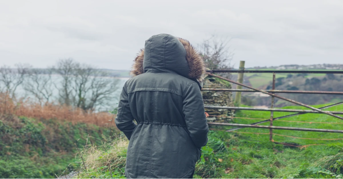a picture of a woman in the country wearing a coat