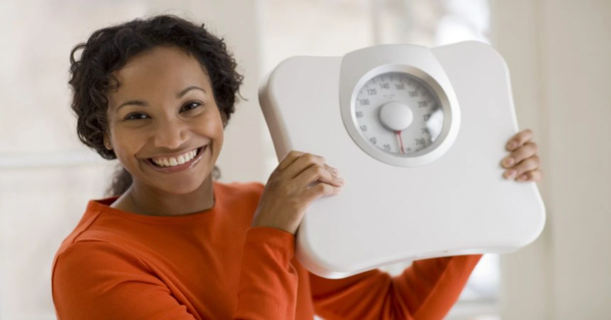 a woman in red holding up a scale